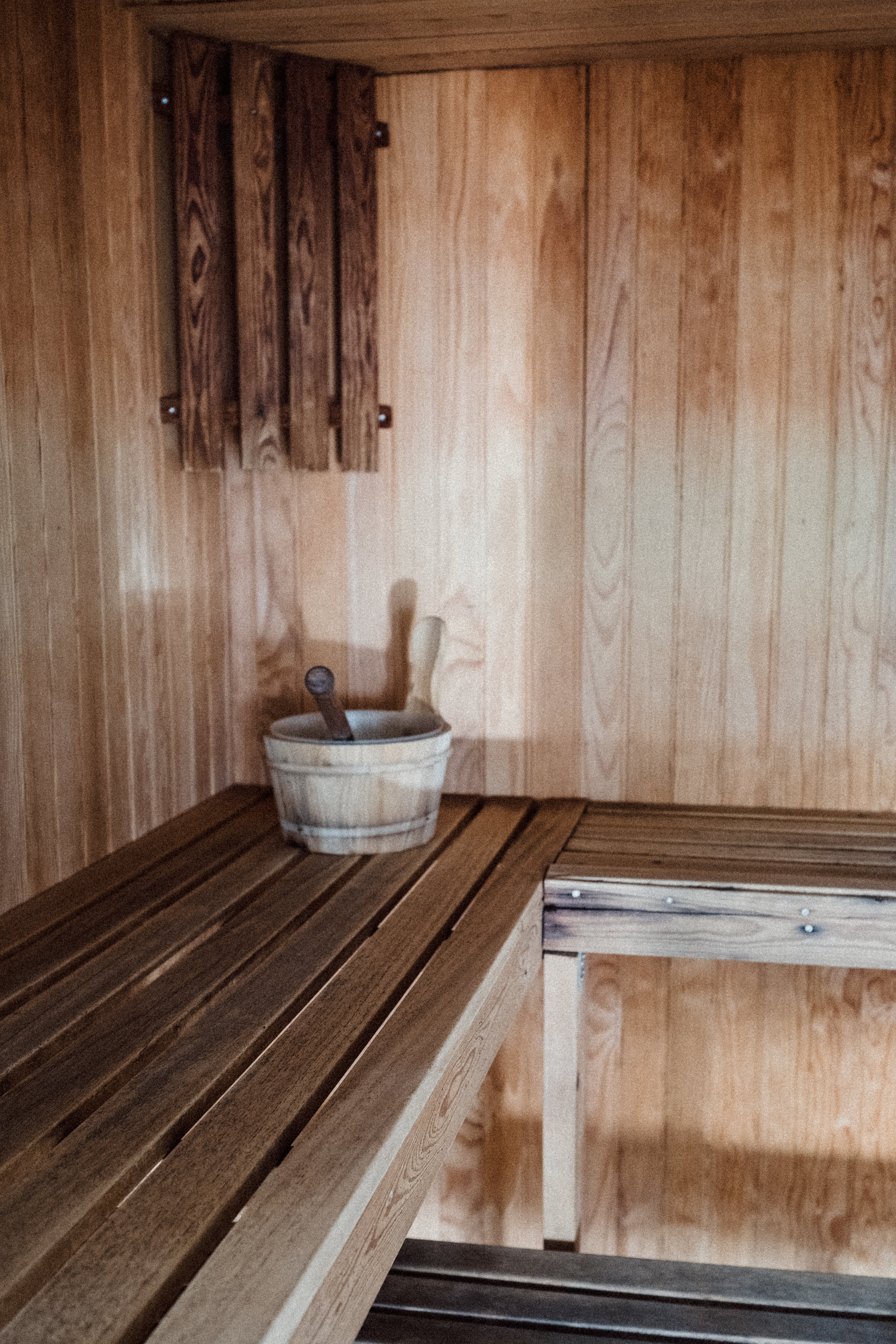 Inside a cedar sauna cabin with slatted wooden benches lit by warm low light