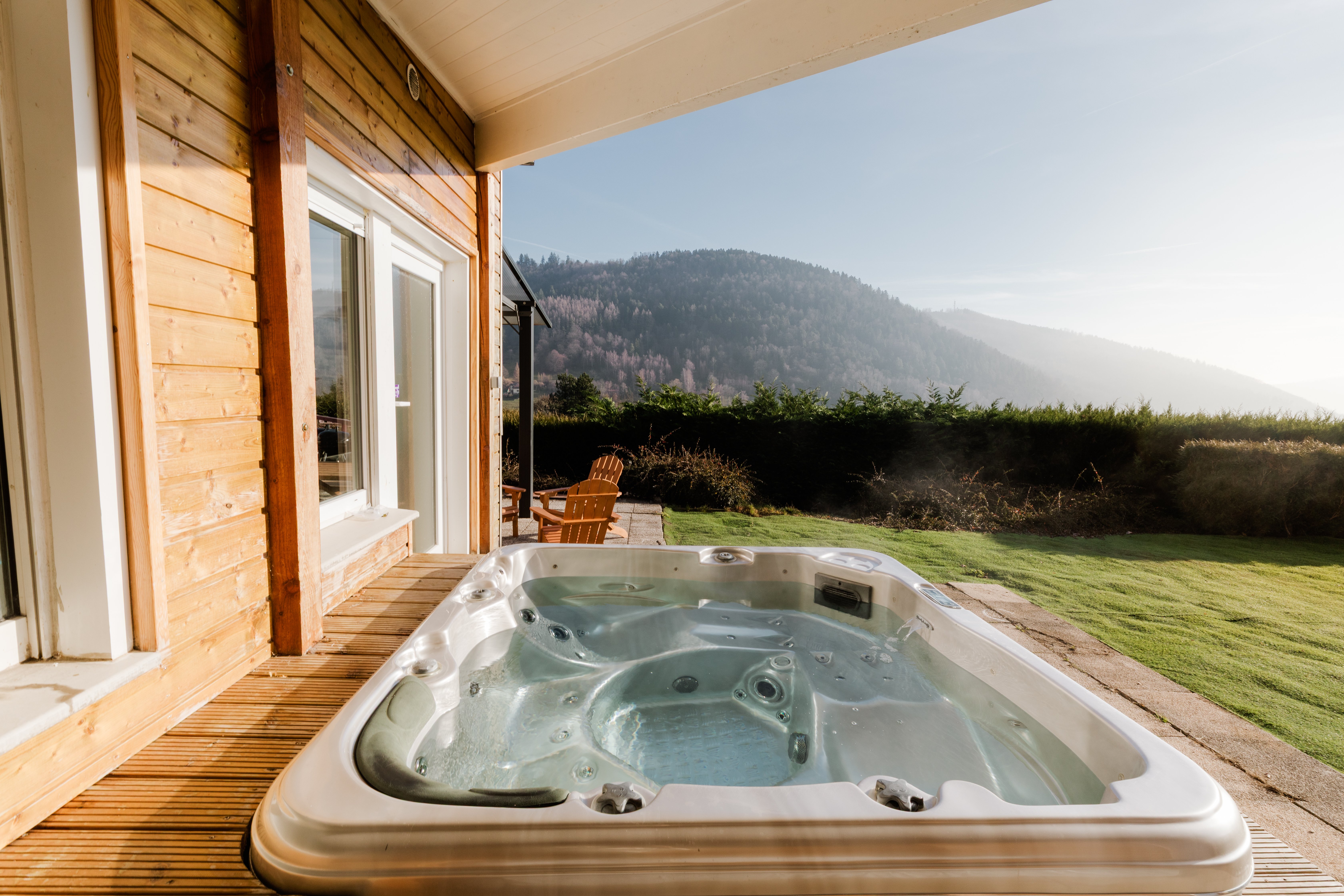 Steaming outdoor hot tub on a wooden deck looking out to a Vosges mountain ridge at golden hour